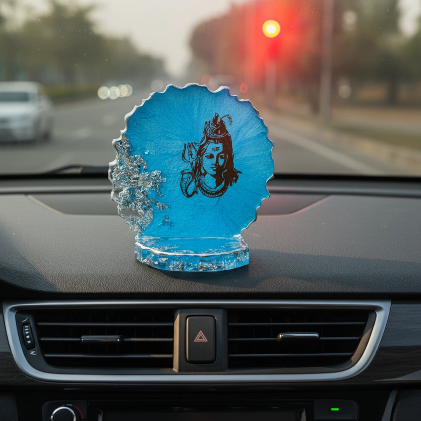 Blue decorative car dashboard showpiece with a lord siva design on a car dashboard with a traffic light in the background.